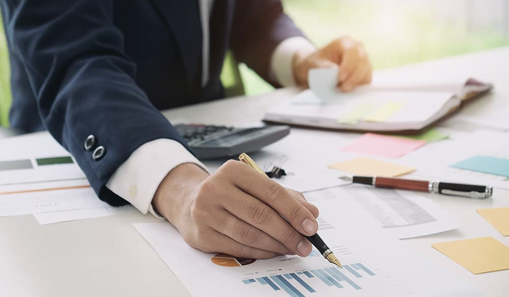 CPA doing financial accounting writing on a chart and using a calculator